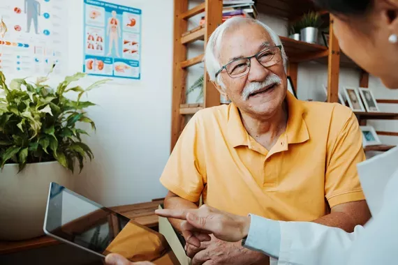 A healthcare professional and a senior patient in a conversation using a tablet A healthcare professional and a senior patient in a conversation using a tablet