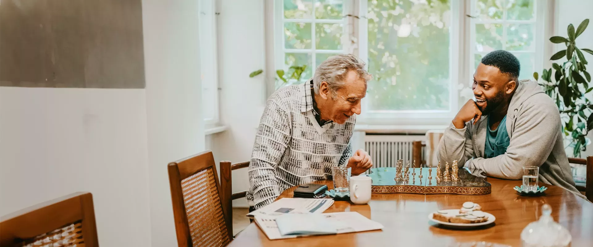 Young and senior man laughing while playing chess